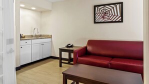 Un espace de vie compact comprenant un coin cuisine, un canapé en cuir rouge et une petite table.