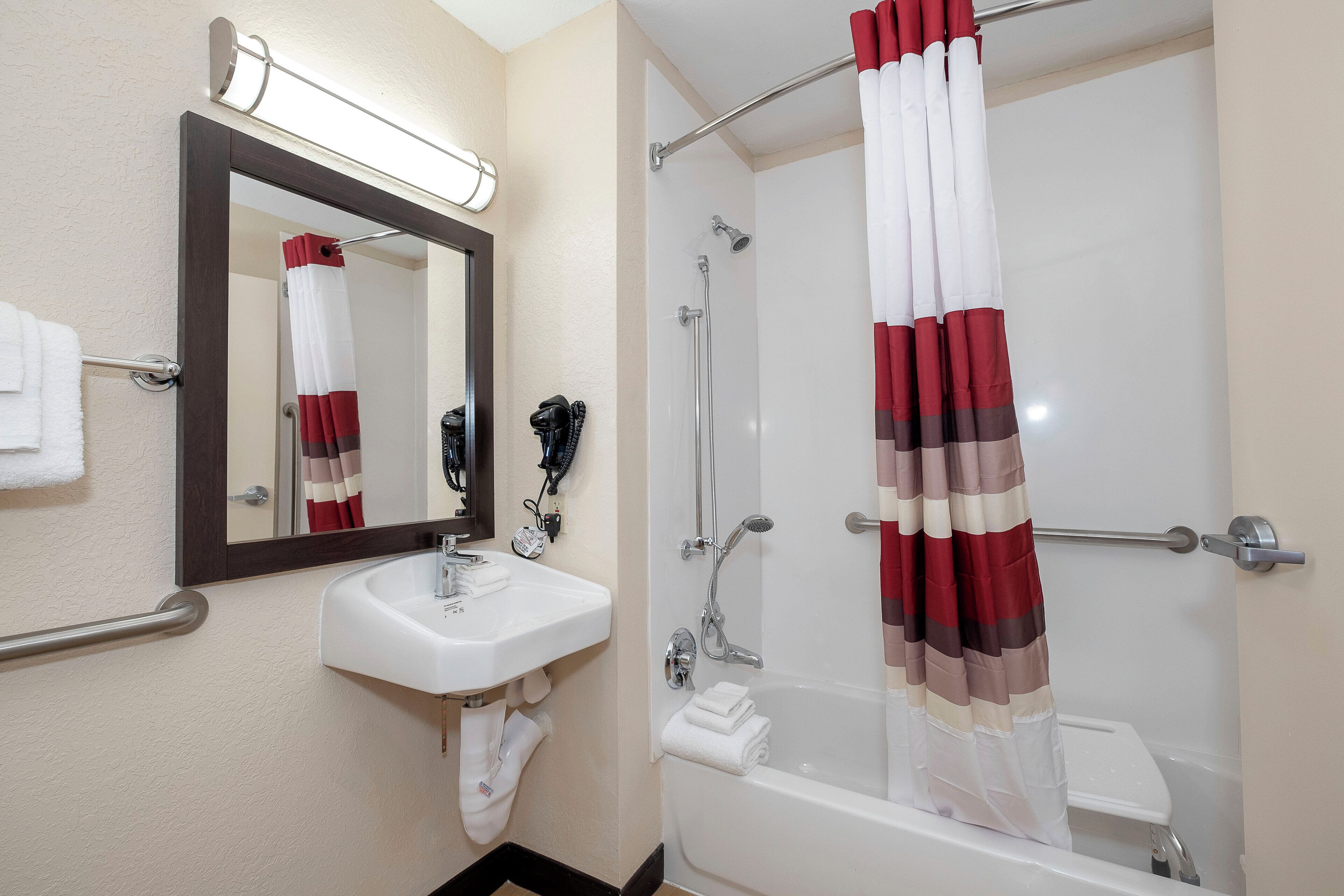 Une salle de bain équipée d’un lavabo, d’un miroir, d’une douche et d’un porte-serviettes.