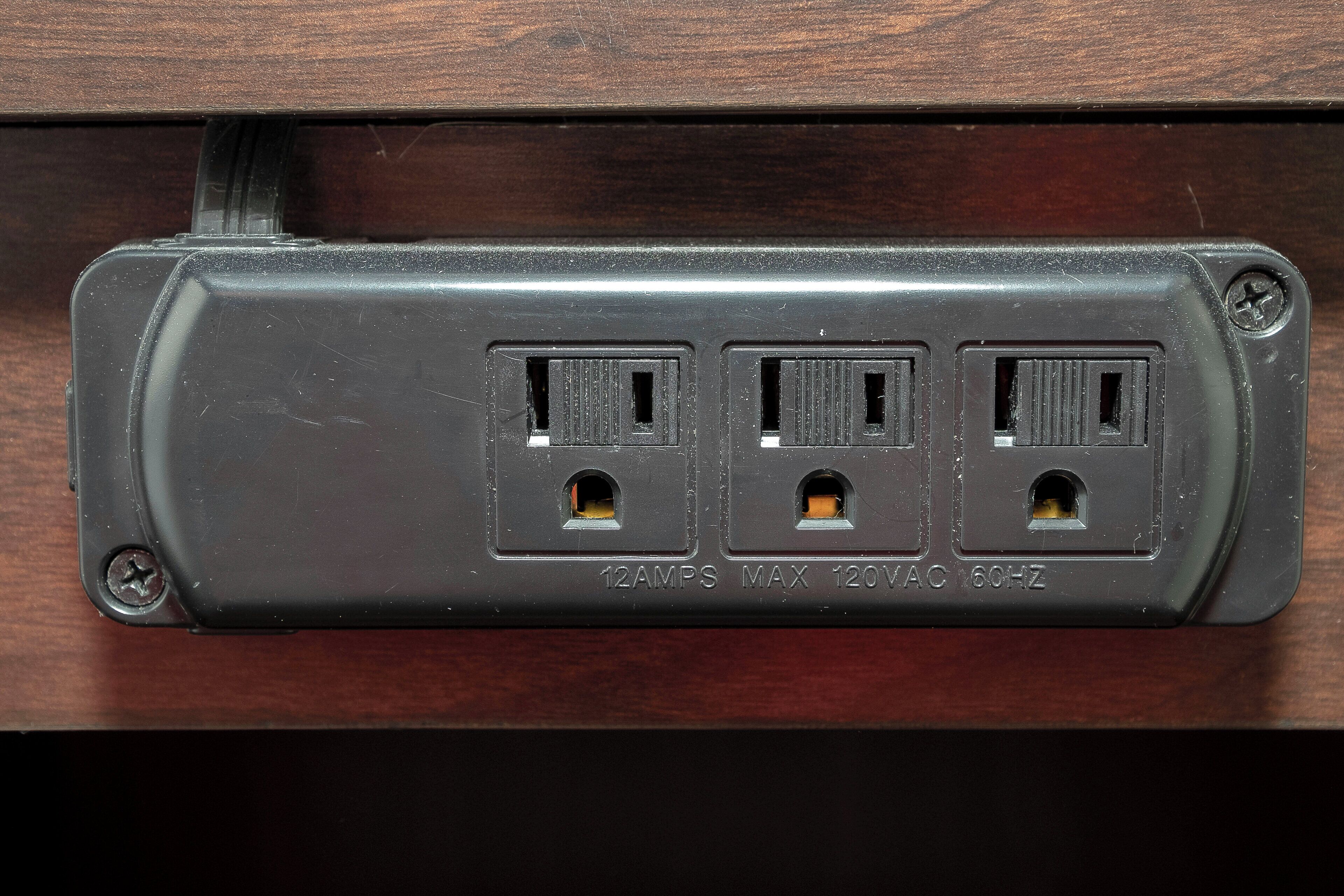 A power strip with three outlets, a USB port, and a label indicating 12 amps, 120V, 60Hz.