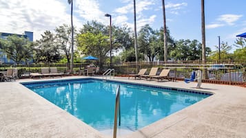 Una piscina al aire libre, sombrillas, sillones reclinables de piscina