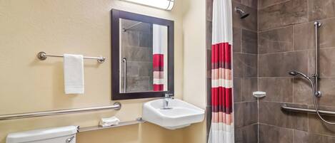 Een badkamer met toilet, wastafel, spiegel, douche en een handdoekhouder.