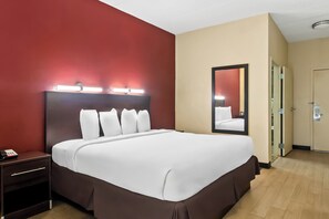 Une chambre d’hôtel avec un grand lit, une table de chevet, un miroir et une porte.