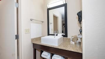A bathroom with a white sink, a mirror, a towel rack, and a telephone.