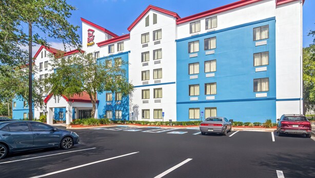 A hotel with a blue and white facade, multiple floors, and a parking lot with several cars.