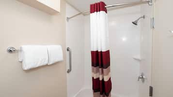 A shower with a glass enclosure, a white towel on a rack, and a red and white shower curtain.