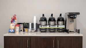 Un espace dédié au café, équipé de plusieurs machines à café, d’un distributeur d’eau et d’une variété de produits à base de café et de sucre.