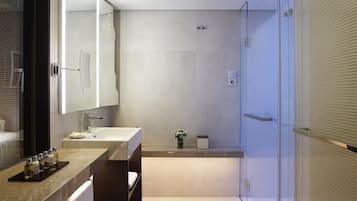 A modern bathroom with a large mirror, two sinks, a shower, and a towel rack.