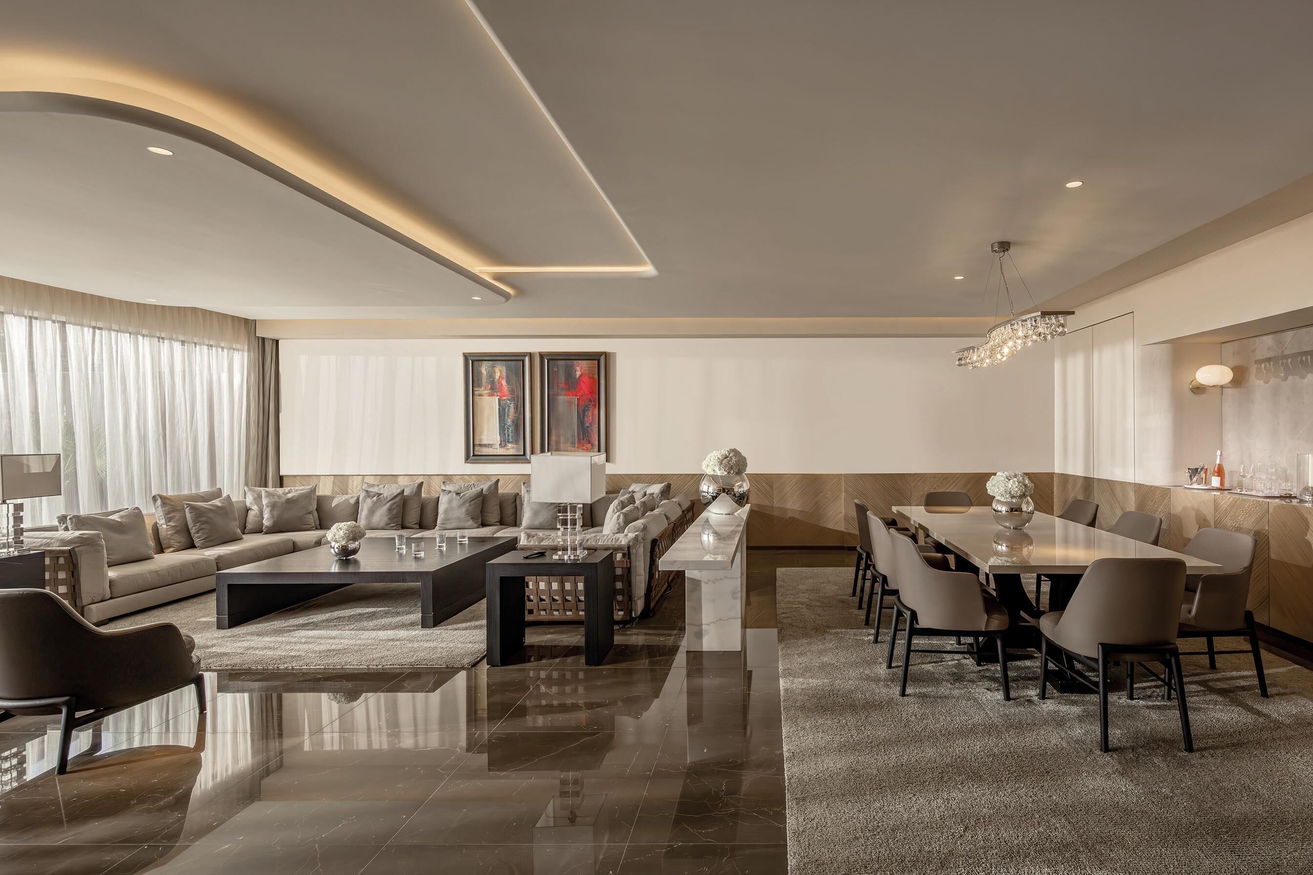 A modern living room with a sofa, coffee table, and dining area with chairs.