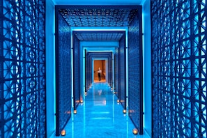 A corridor with a grid-like pattern on the walls and a reflective floor, leading to a door at the end. - Four Seasons Hotel (Limassol)