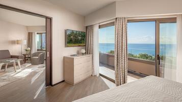 A hotel room with a large bed, a desk, a chair, and a view of the sea.
