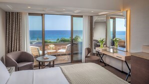 A hotel room with a bed, a desk, a chair, and a balcony with a view of the sea. - Four Seasons Hotel (Limassol)