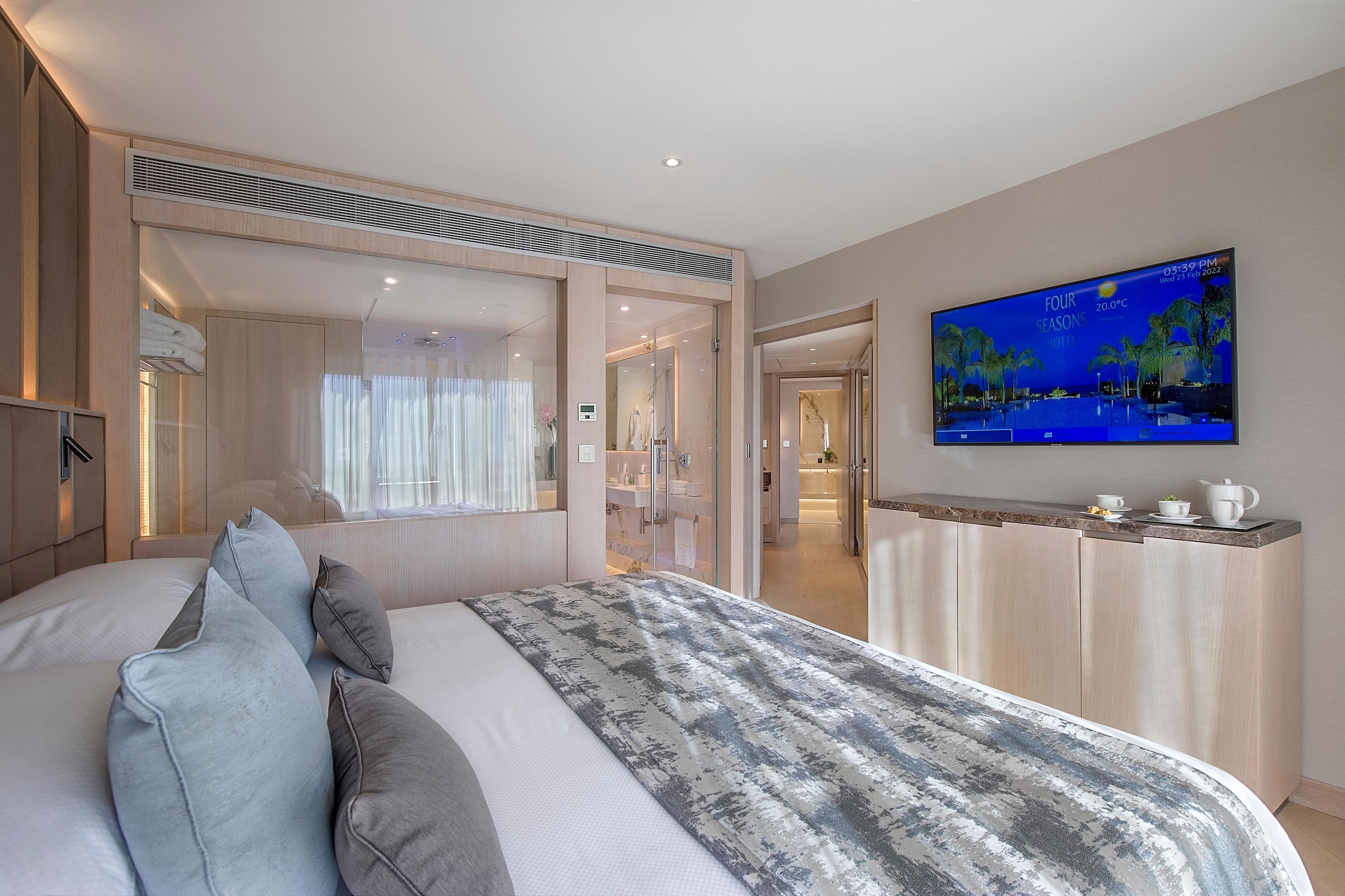 Una habitación de hotel moderna con una cama grande, un televisor en la pared y vistas al área de la piscina.