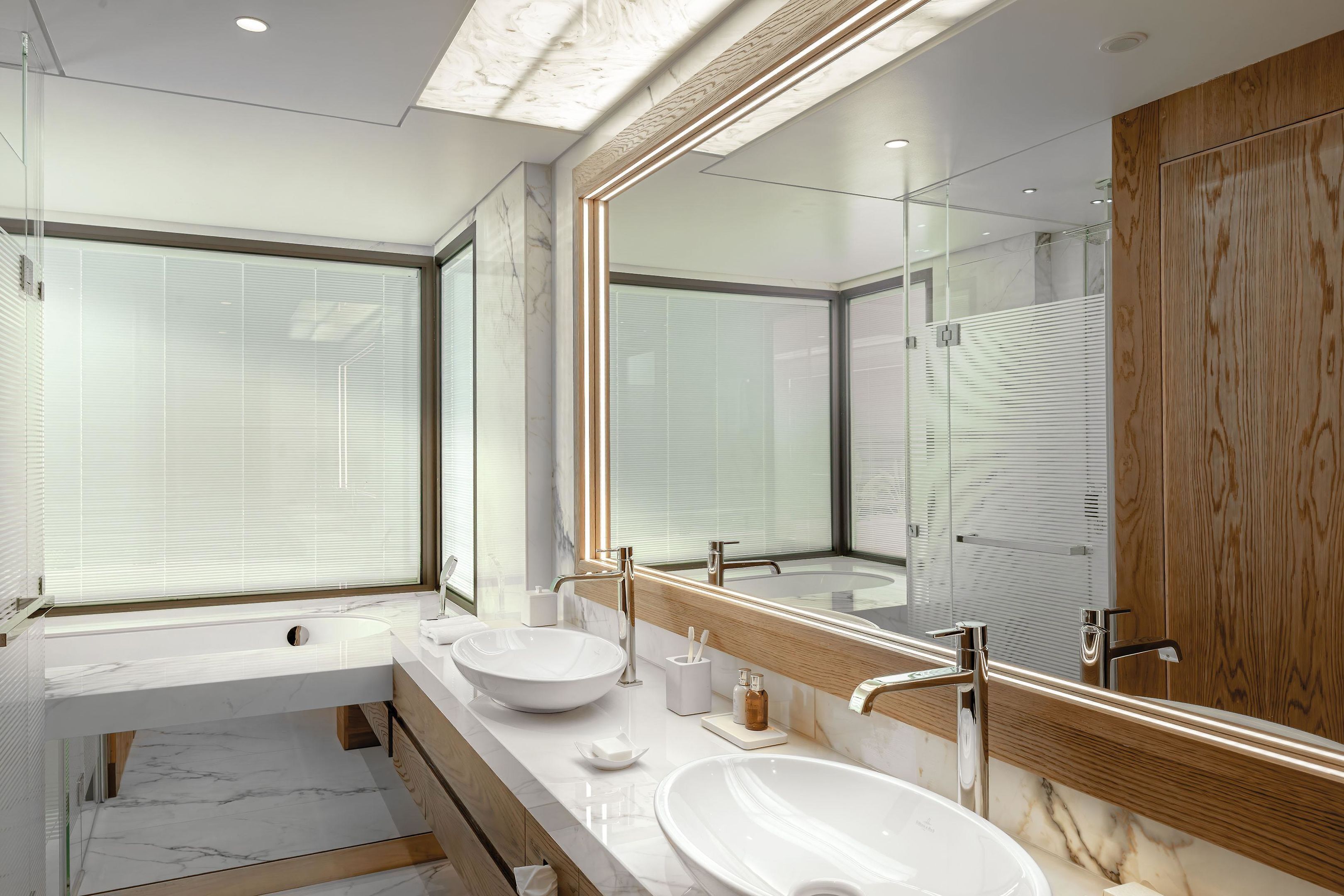 A modern bathroom with two sinks, a large mirror, and a wooden vanity.