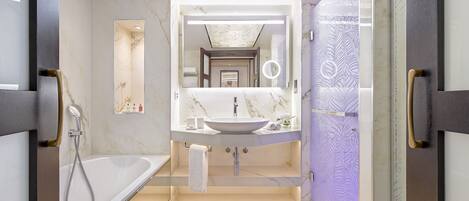 A modern bathroom with a large mirror, a bathtub, and a vanity with a sink.