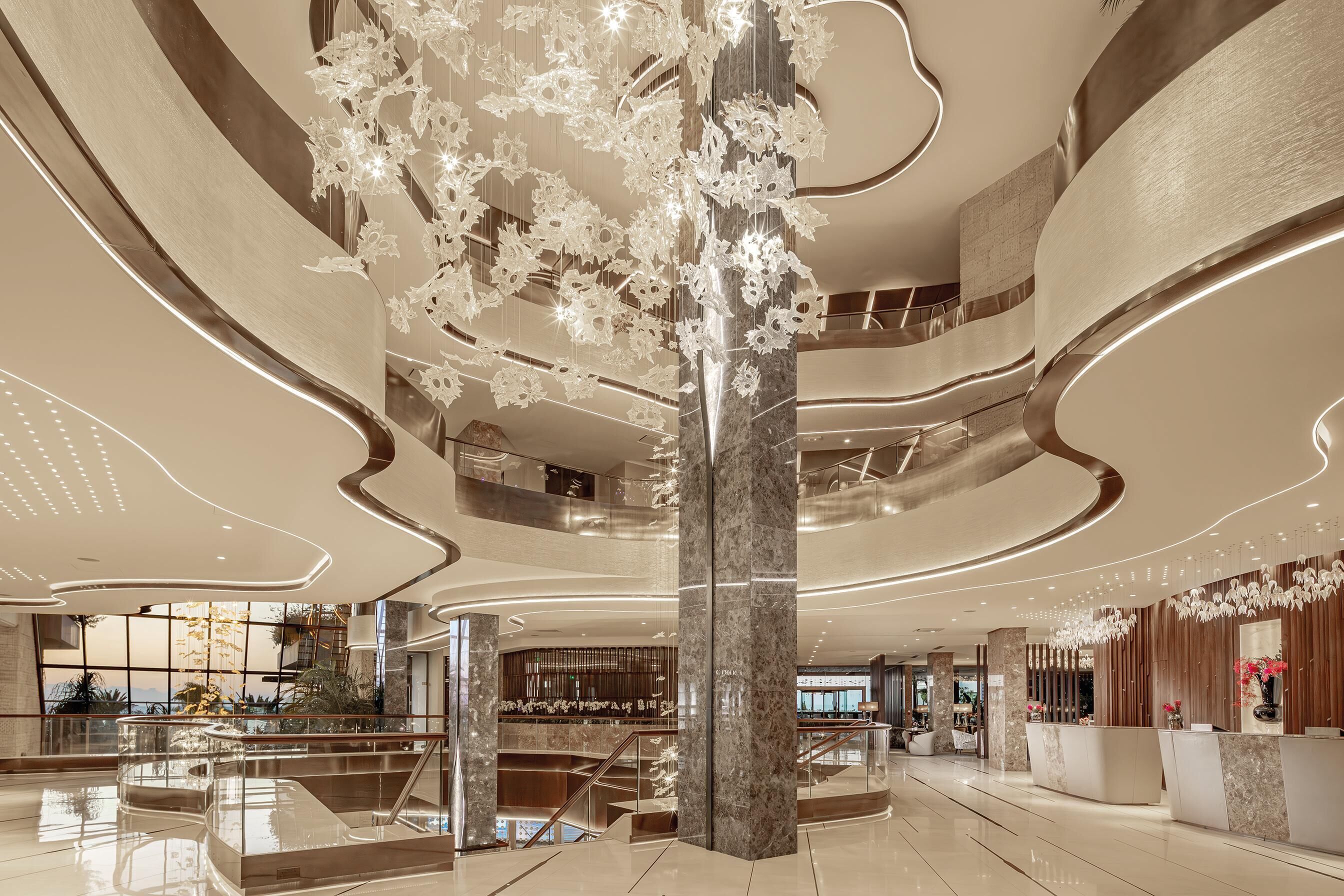 A spacious lobby with a central column, multiple levels, and a modern chandelier.