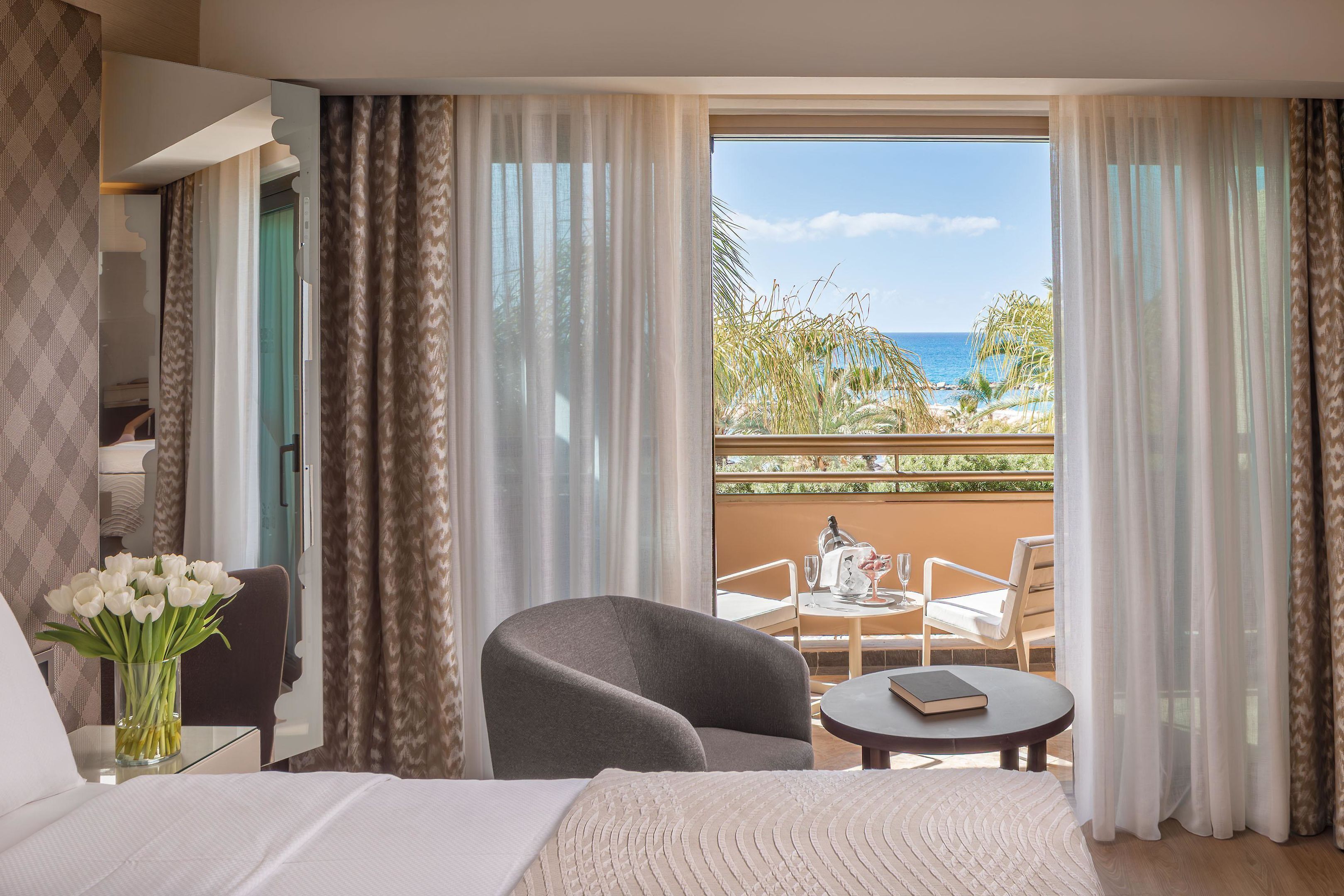 Una habitación de hotel con una cama, una silla, una mesita y vistas al mar.
