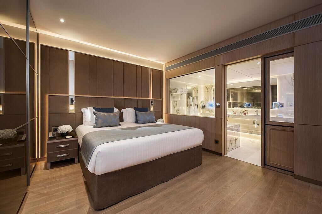 A modern bedroom with a large bed, bedside tables, and a walk-in closet.