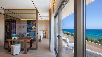 Habitación de hotel moderna con balcón, suelo de madera y vistas al mar.