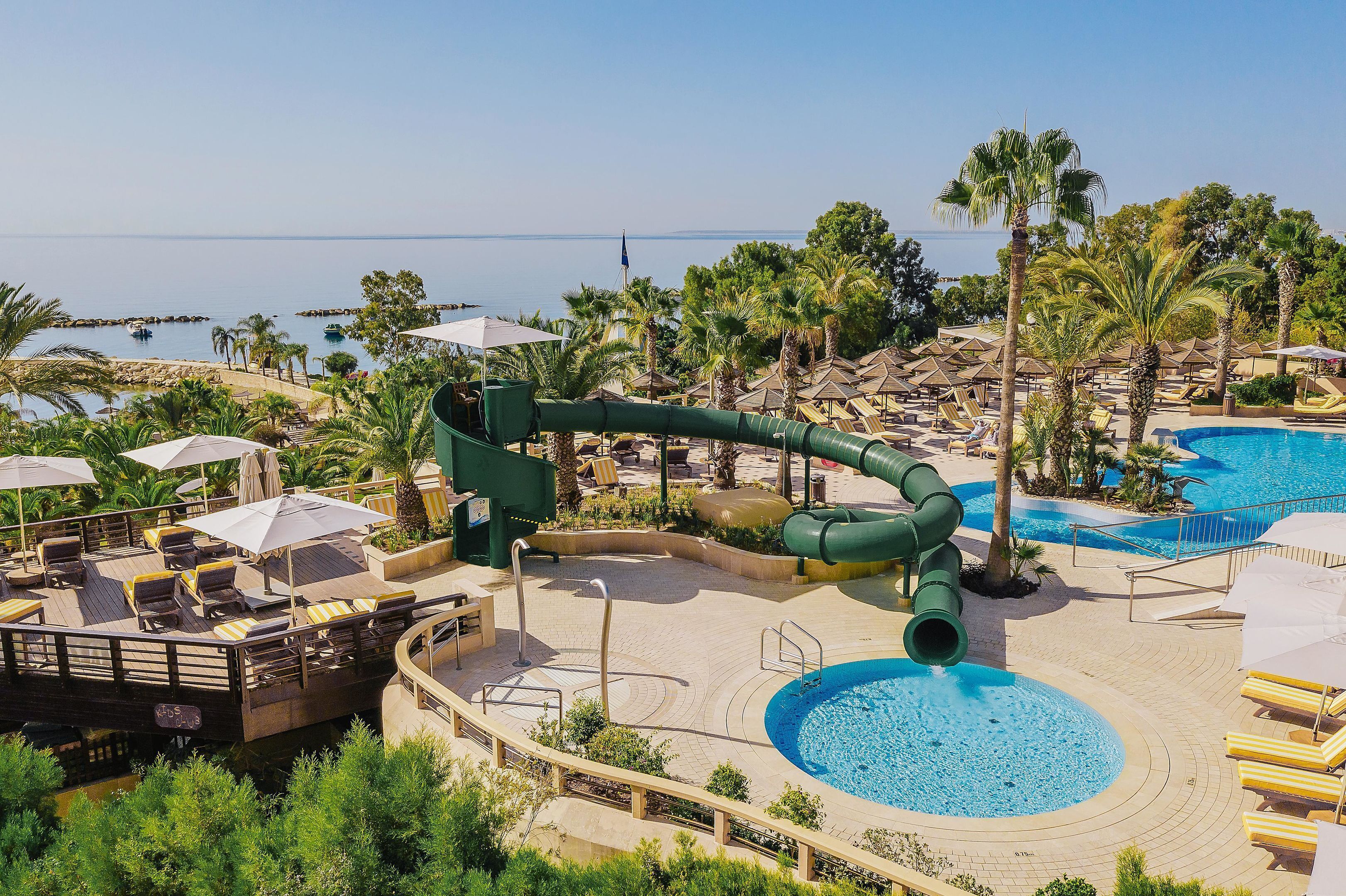 A resort with a water slide, pool, and lounge area with umbrellas.