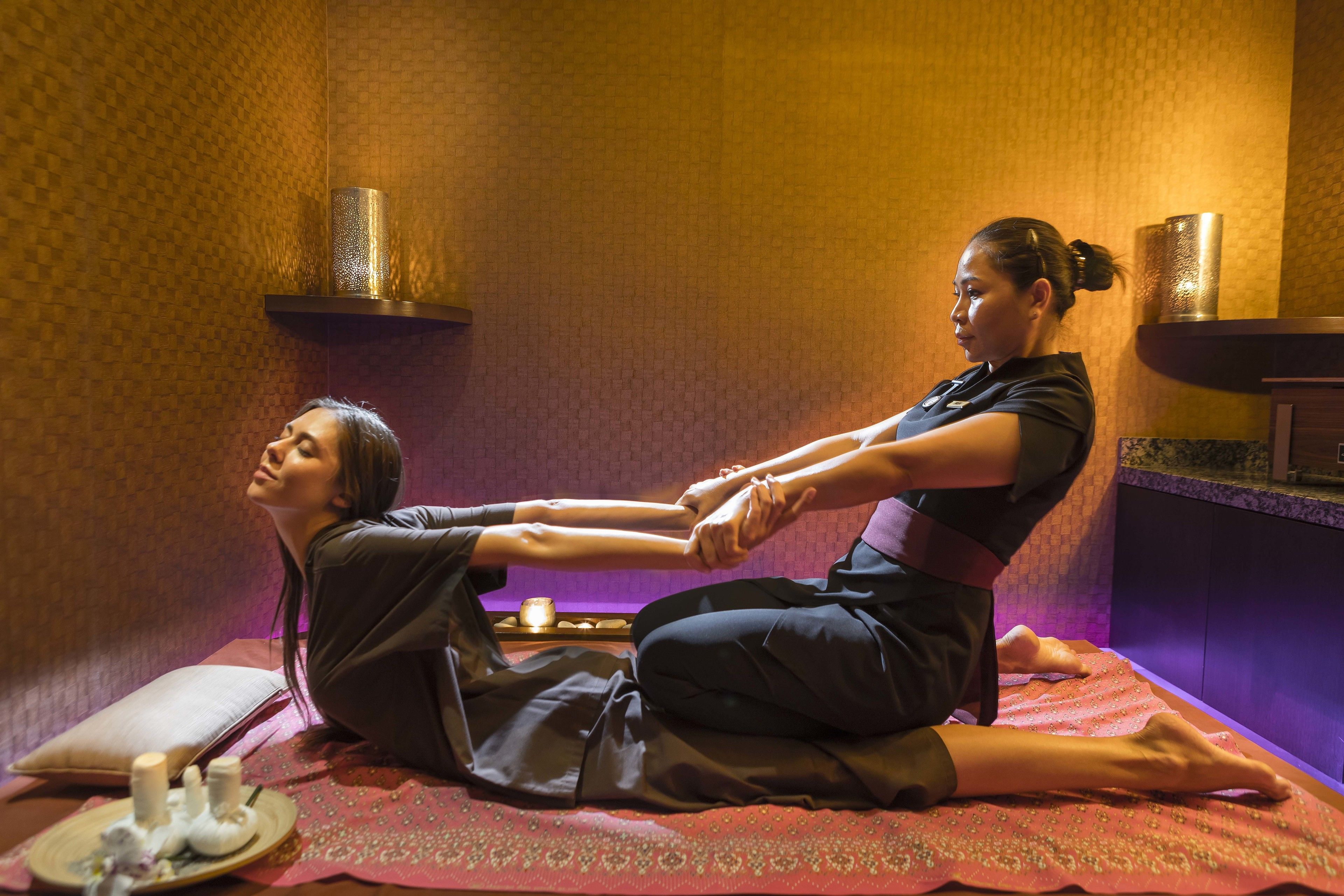 A massage therapy session in a room with patterned walls, a massage table, and candles.