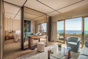 A modern hotel room with a large balcony, a bed, a sitting area, and a dining table. - Four Seasons Hotel (Limassol)