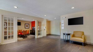 A spacious room with wooden flooring, a dining area with orange chairs, and a sofa. - Extended Stay America Select Suites - Atlanta - Vinings (Atlanta)