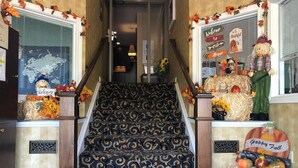 Una escalera con alfombra estampada, flanqueada por elementos decorativos y letreros de bienvenida.