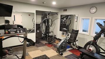 A gym with various exercise equipment, including a treadmill, stationary bike, and weight machines.