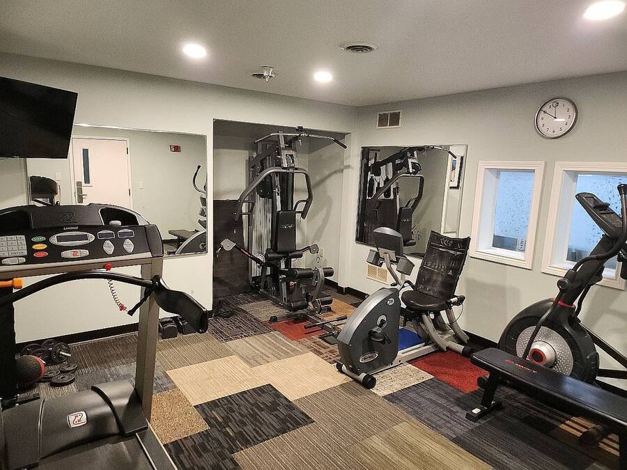 Un gimnasio con diversos equipos de ejercicio, como cintas de correr, bicicletas estáticas y máquinas de pesas.