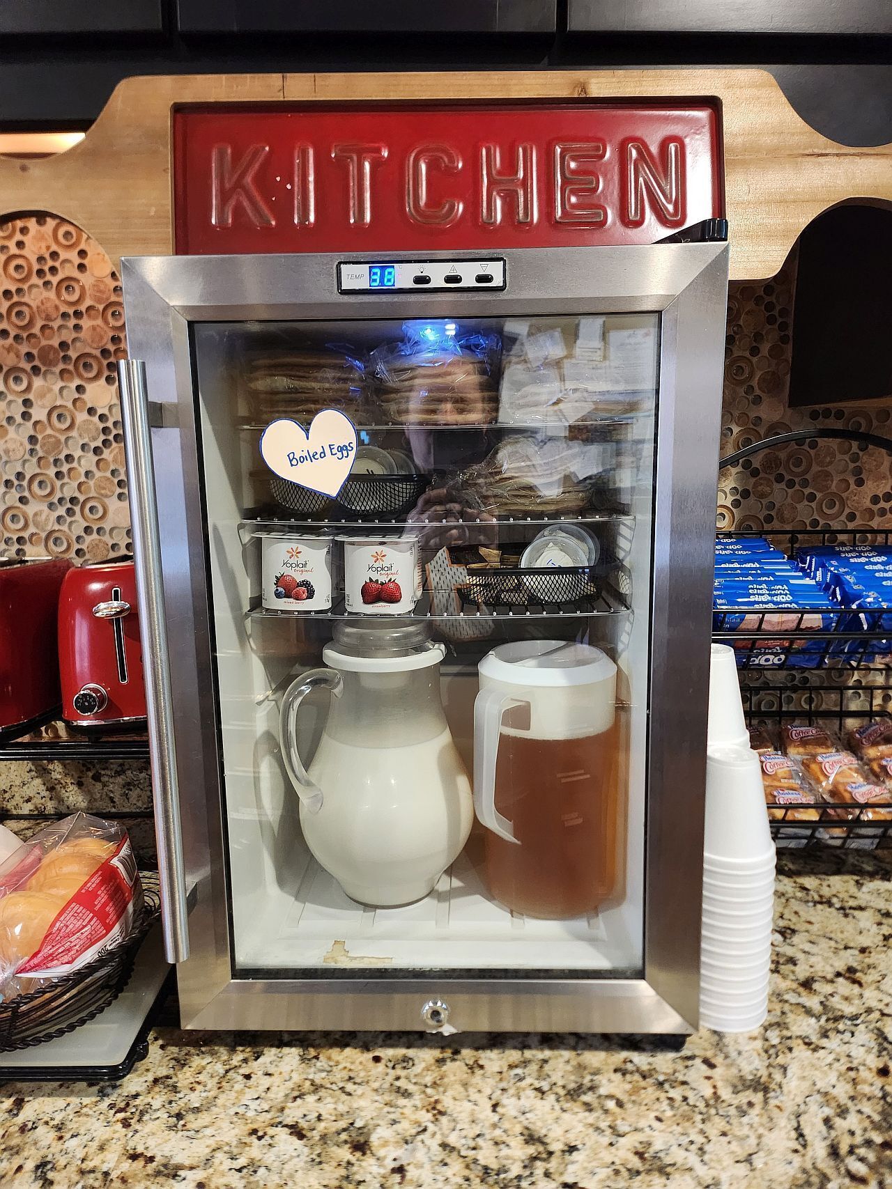 A kitchen vending machine with a heart-shaped sign indicating boiled eggs, a pitcher, and a mug.