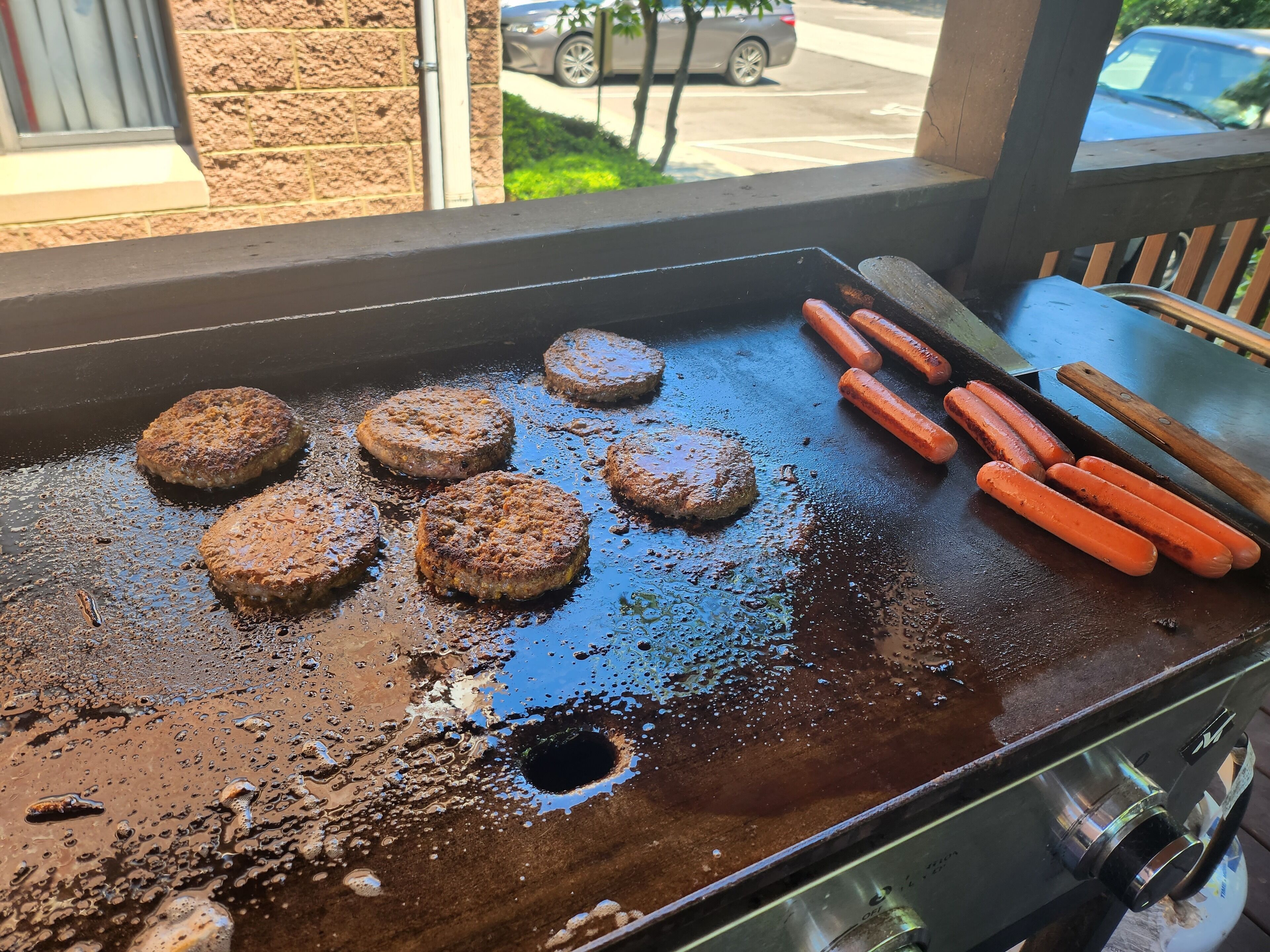 A grill with several burgers and hot dogs cooking.