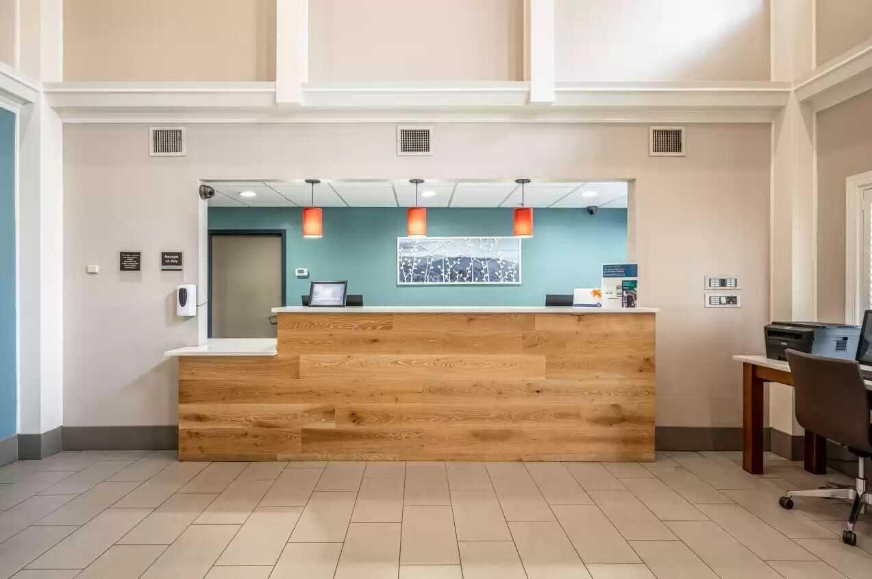 A reception desk with a wooden finish, a blue accent wall, and pendant lighting.