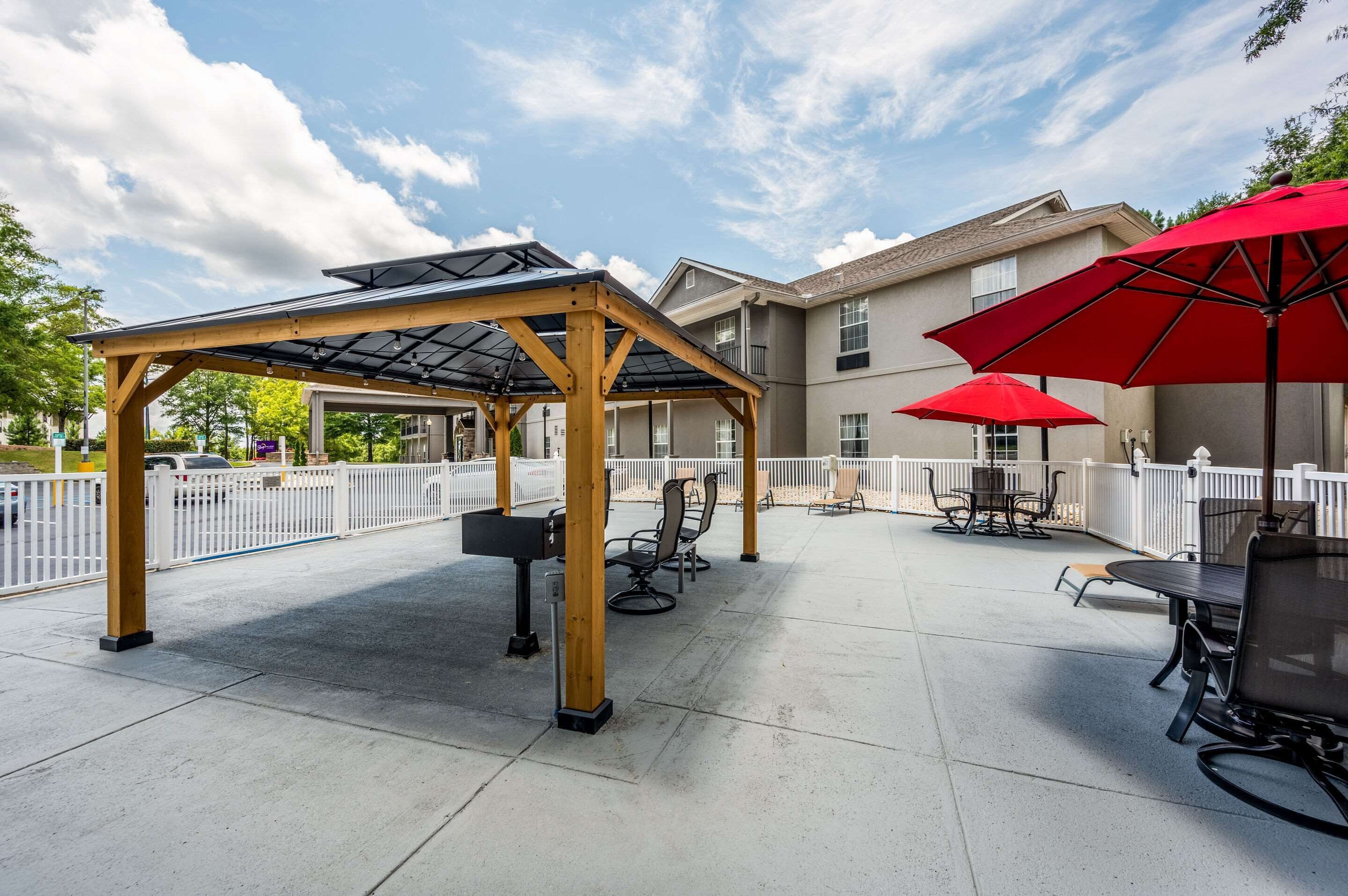 Un espace extérieur aménagé en terrasse, avec une pergola, des parasols rouges et des sièges.