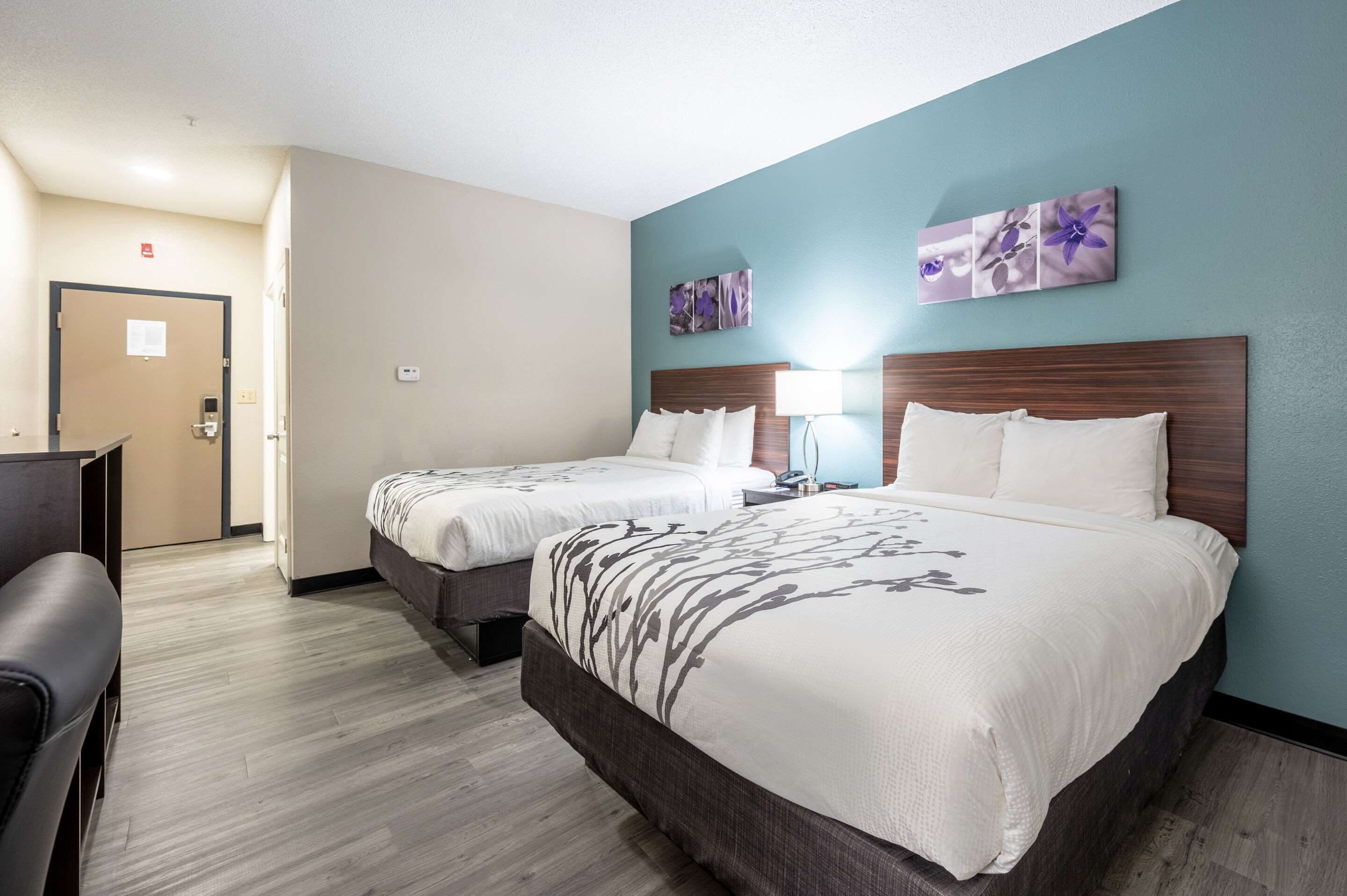 A hotel room with two beds, a desk, and a chair.