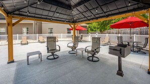 An outdoor patio with metal chairs, a small table, and a grill. - Sleep Inn & Suites Birmingham - Hoover (Birmingham)
