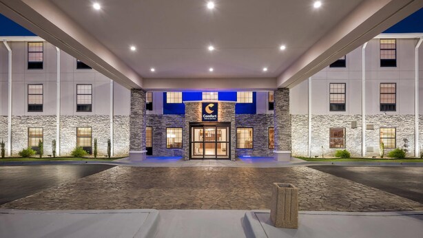 A hotel entrance with a stone facade, a blue-lit entrance, and a sign reading "Comfort Inn." - Comfort Inn & Suites River City Decatur (Decatur)
