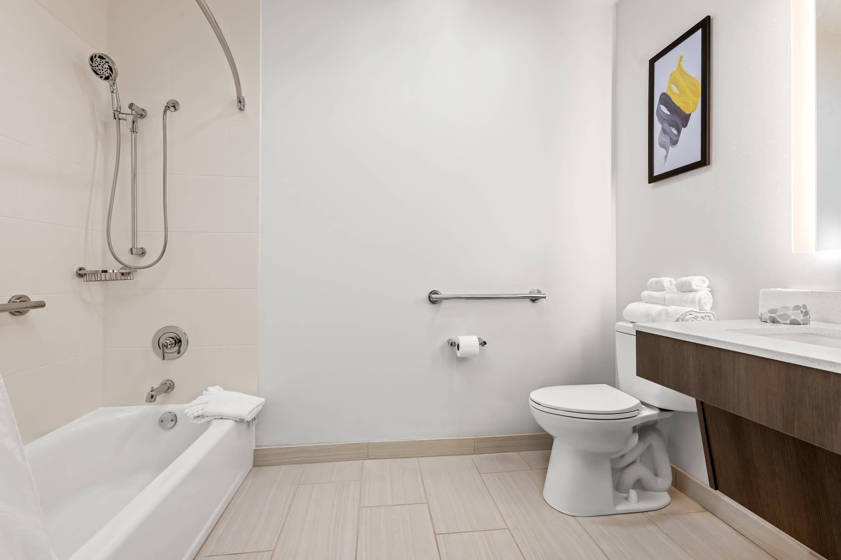 A modern bathroom with a bathtub, toilet, and shower.