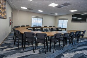 Conference room with a long table and 12 chairs, a flat-screen TV, and windows with blinds.