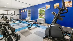A gym with exercise equipment, a blue wall, and a window. - Comfort Inn & Suites River City Decatur (Decatur)