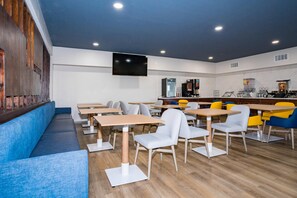 Enjoy meals and presentations in this dining area with multiple tables and chairs, a flat-screen TV, and recessed lighting.