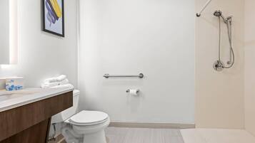 A modern bathroom with a toilet, a shower, and a vanity with a towel rack.