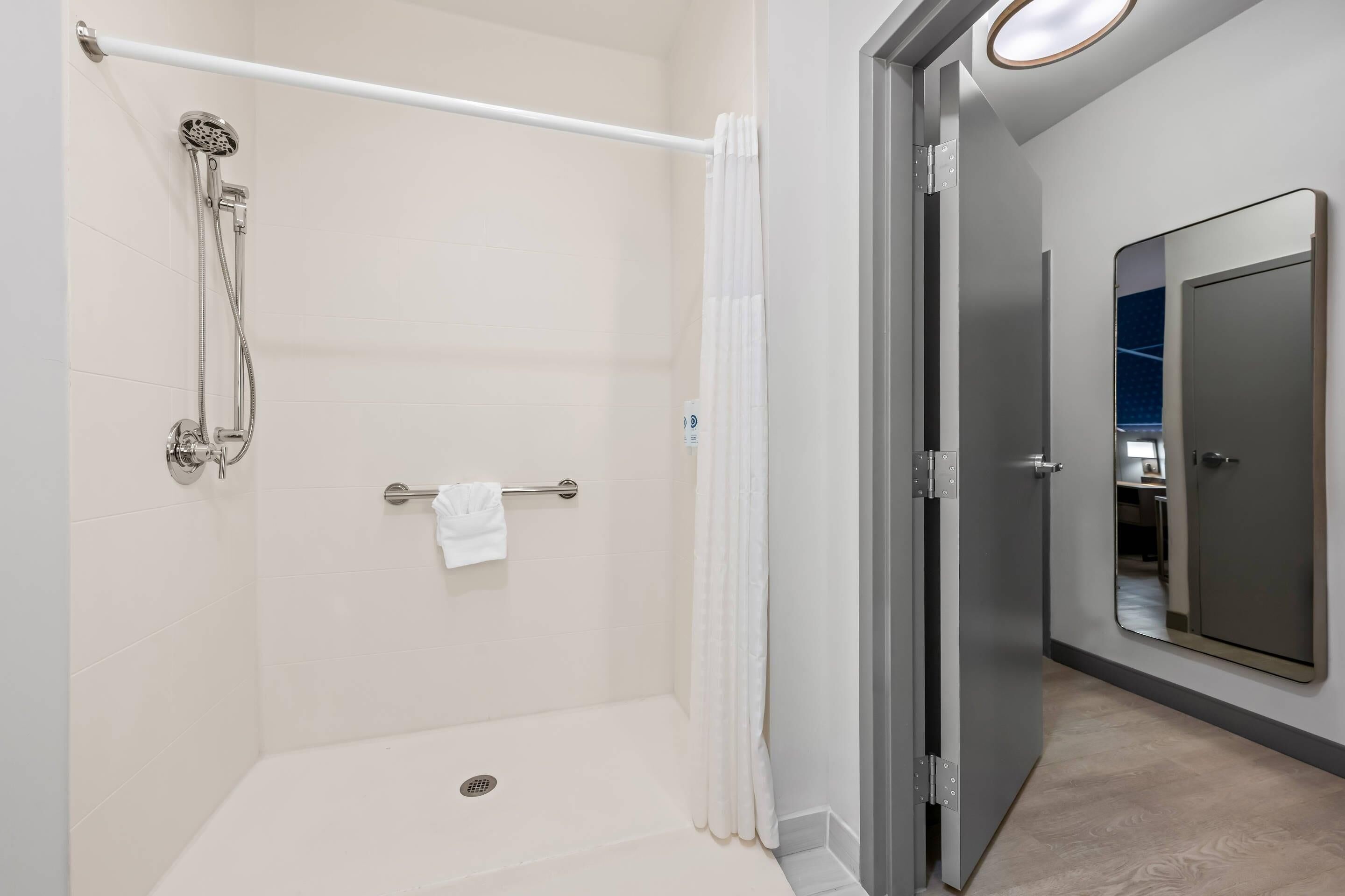 Un baño moderno con ducha a ras de suelo, un perchero y un espejo.