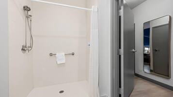 Un baño moderno con ducha a ras de suelo, un perchero y un espejo.