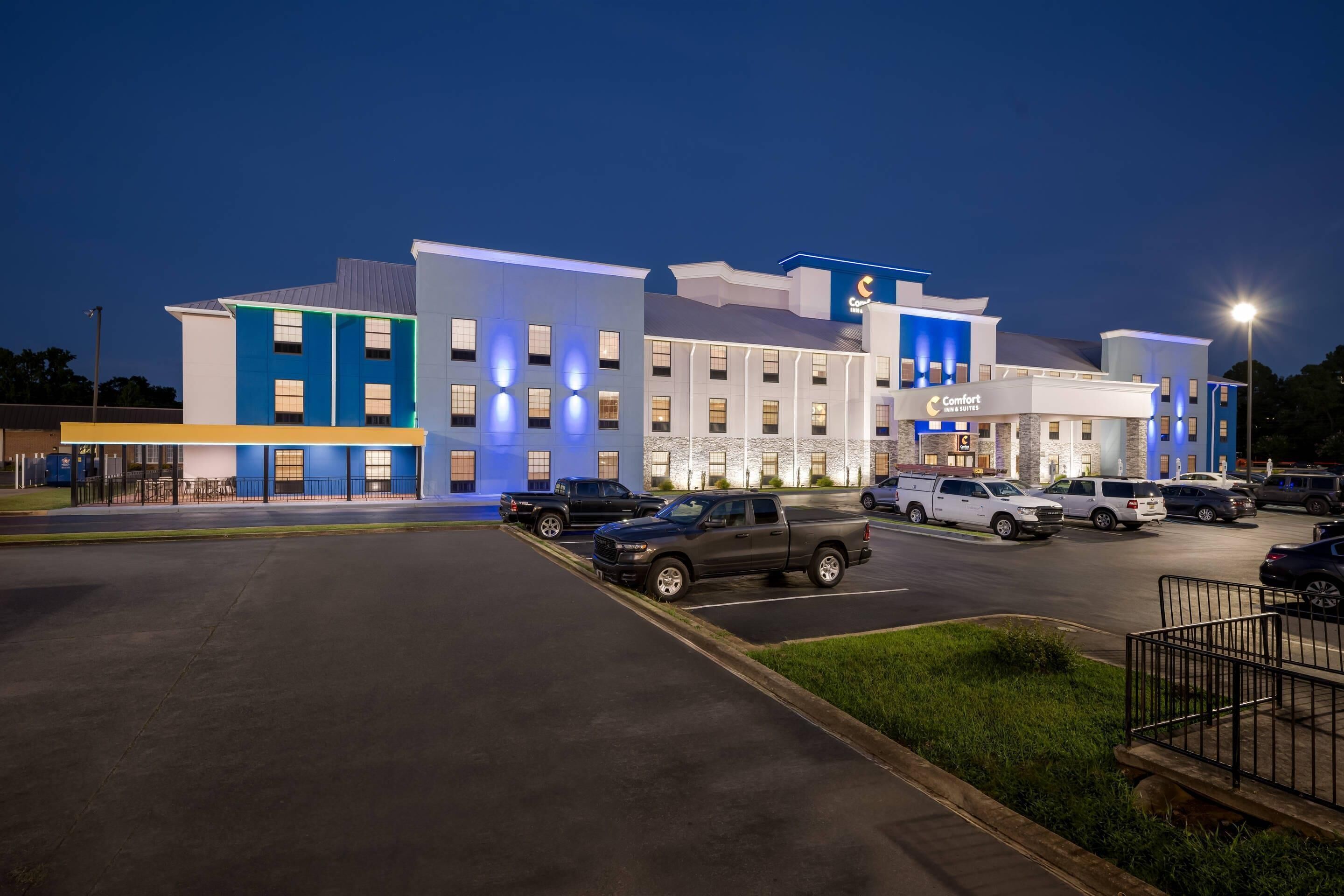 A hotel with a modern design, featuring multiple floors and a parking lot with several vehicles.