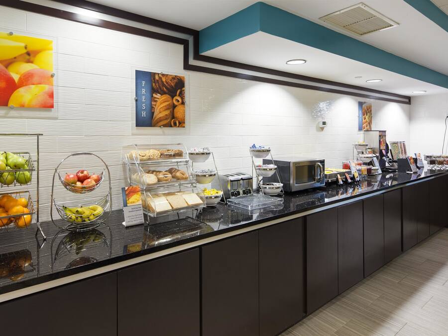 A breakfast bar with various fruits, pastries, and a coffee machine.