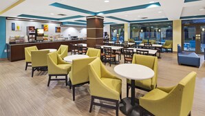 A modern dining area with yellow chairs and round tables, a counter with a beverage dispenser, and a view through large windows. - Best Western Plus Birmingham Inn & Suites (Birmingham)