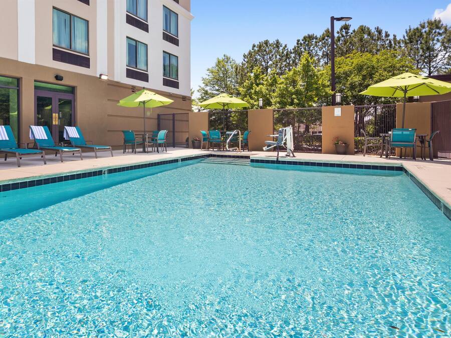 A swimming pool with clear blue water, surrounded by lounge chairs and umbrellas.