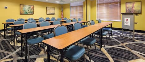A conference room with multiple tables and chairs, a podium with a plaque, and an American flag.