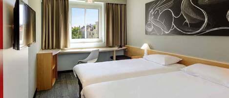 A hotel room with two beds, a desk, a chair, a TV, and a window with curtains.