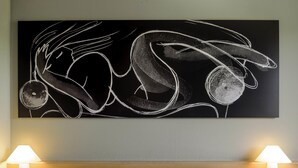 A hotel room with a large abstract painting, two bedside lamps, and a neatly made bed with white linens. - ibis Augsburg Koenigsplatz (Augsburg)